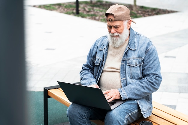 Anciano con laptop al aire libre en la ciudad