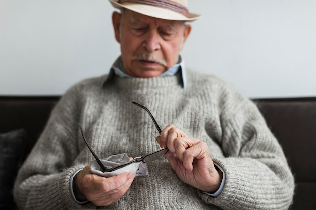 Anciano limpiando sus gafas en un hogar de ancianos