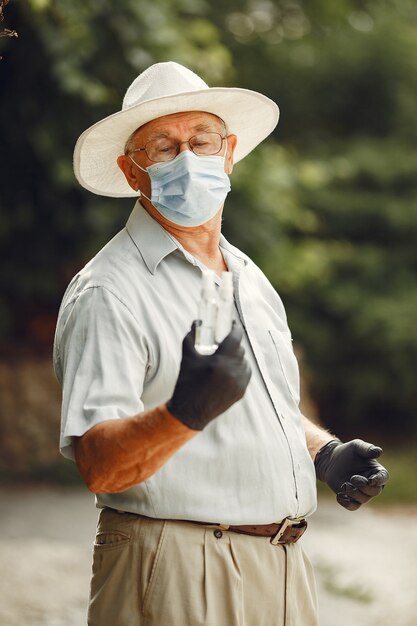 Anciano con una máscara médica. Hombre en el parque. Tema de coronavirus.