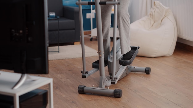 Foto gratuita anciano montando bicicleta estacionaria y haciendo ejercicio en casa. mujer mayor haciendo entrenamiento cardiovascular con bicicleta para practicar fitness y deporte. adulto jubilado que usa equipo de entrenamiento