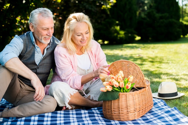 Anciano y mujer mirando la canasta de picnic