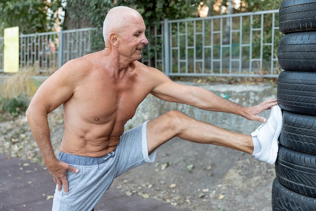 Anciano musculoso estirando al aire libre