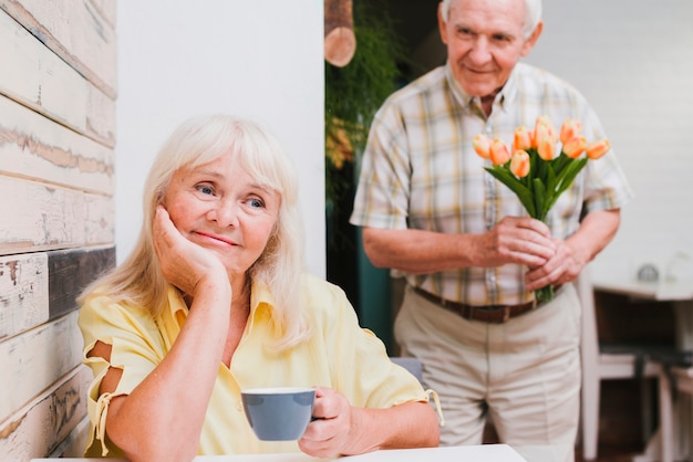 Foto gratuita anciano de pie detrás amado con flores.