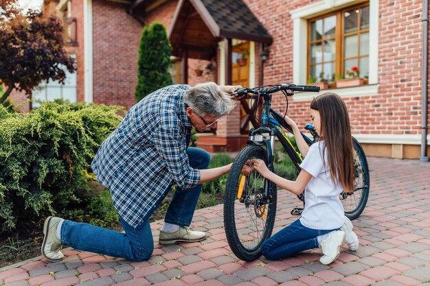 Anciano reparando bicicleta para sus hijos. Tiempo en casa, concepto de descanso.