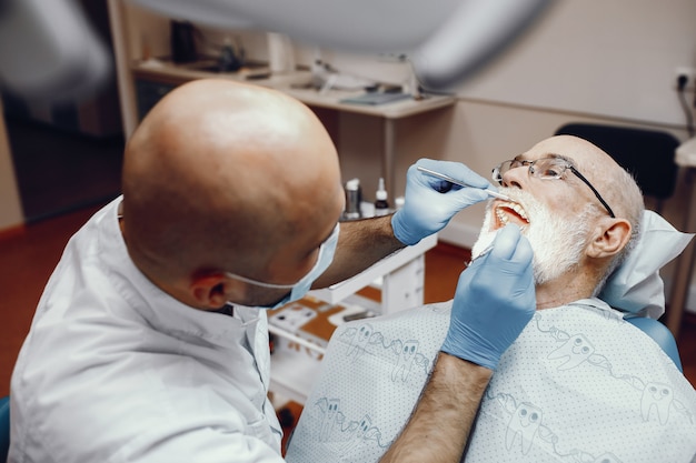 Anciano sentado en la oficina del dentista