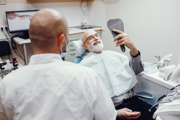 Anciano sentado en la oficina del dentista