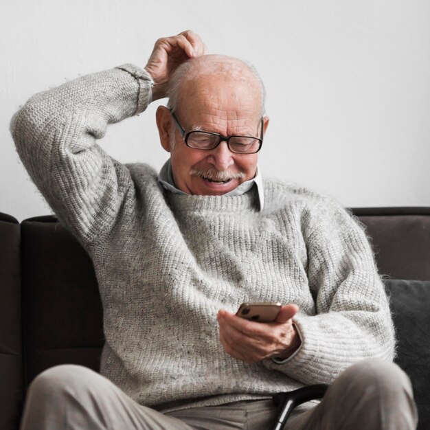 Anciano sonriente en un hogar de ancianos con smartphone