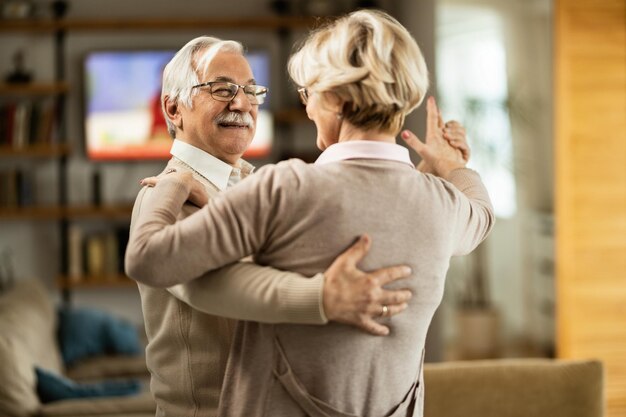 Un anciano sonriente y su esposa bailando en casa