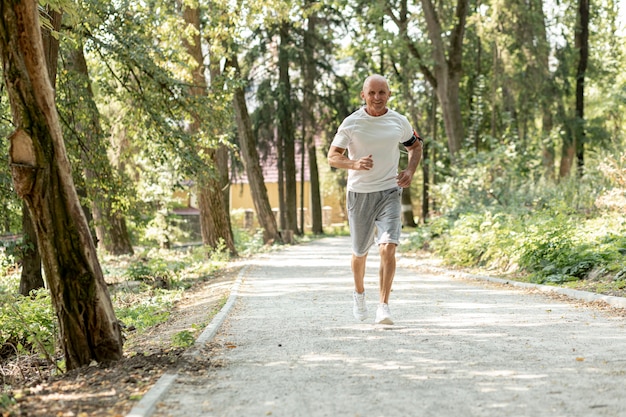 Anciano de tiro completo corriendo en el bosque