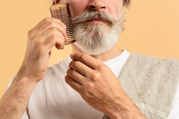 Anciano con toalla peinándose la barba