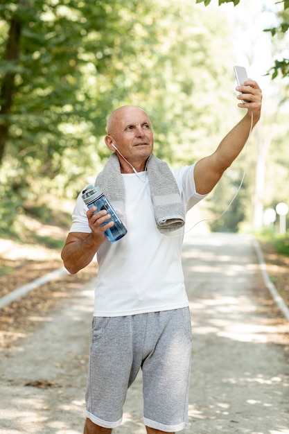 Foto gratuita anciano tomando selfie en ropa deportiva con toalla