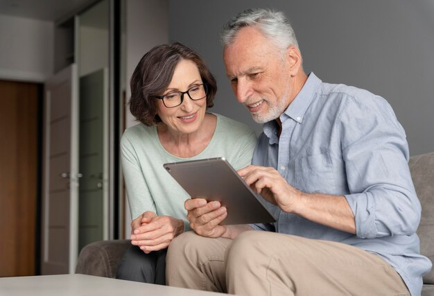 Ancianos sonrientes de tiro medio con tableta