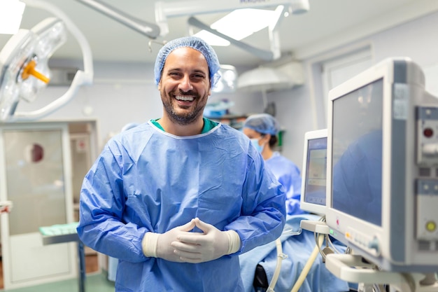 Anestesista que trabaja en el quirófano usando monitores de control de equipo protector mientras seda al paciente antes del procedimiento quirúrgico en el hospital