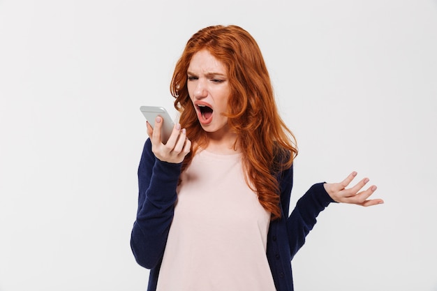 Angry pelirroja jovencita hablando por teléfono móvil y gritando.