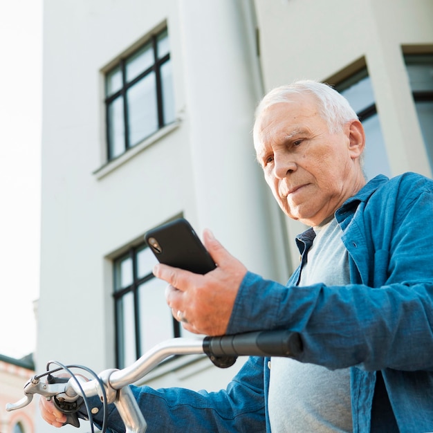 Foto gratuita Ángulo bajo de anciano con bicicleta