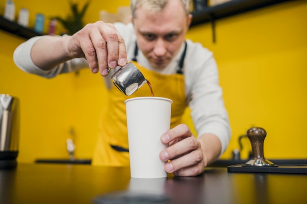 Foto gratuita bajo ángulo de barista vertiendo café