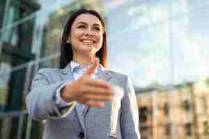 Foto gratuita Ángulo bajo de la empresaria sonriente dando la mano para un apretón de manos al aire libre