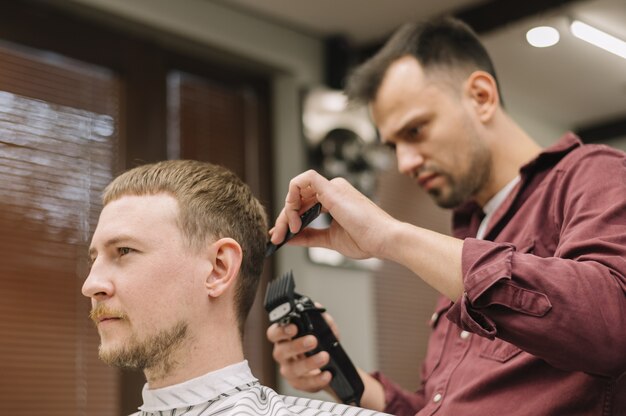 Bajo ángulo de estilista dando un corte de pelo