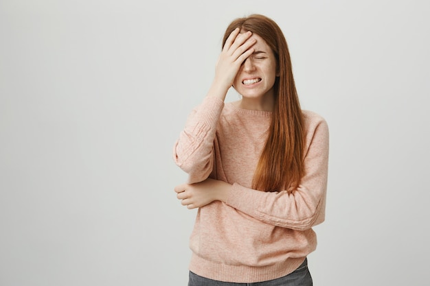 Angustiada chica pelirroja facepalm, sintiéndose frustrado