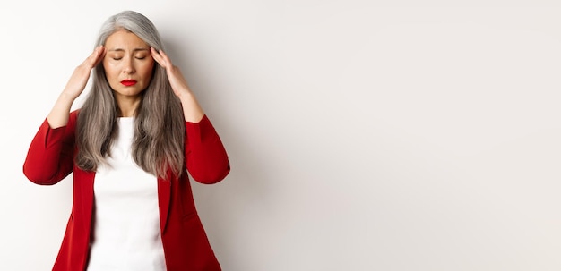 Foto gratuita angustiada mujer de negocios asiática tratando de calmarse masajeando las sienes en la cabeza para calmar el dolor de cabeza stan