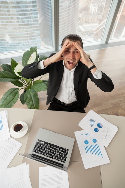 Foto gratuita angustiado hombre de negocios en el trabajo mirando hacia arriba