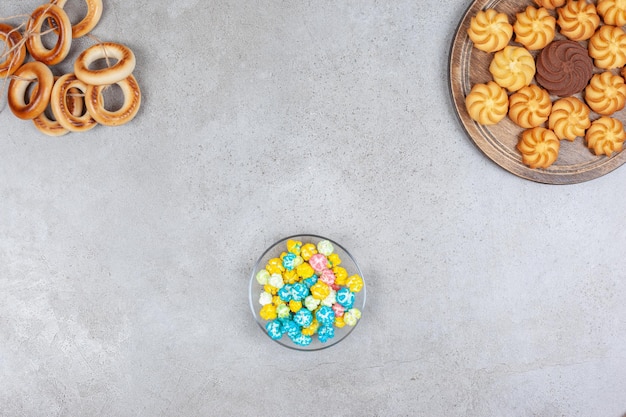 Anillo atado de sushki, un tazón pequeño de dulces de palomitas de maíz y una bandeja de galletas sobre fondo de mármol. Foto de alta calidad