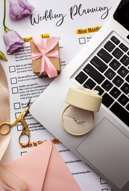 Anillo de bodas en laptop y papeles de invitación