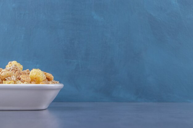 Anillo de maíz con miel y muesli en un bol, sobre la mesa de mármol.