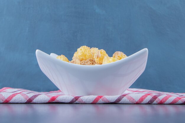 Anillo de maíz con miel y muesli en un recipiente sobre un paño de cocina, sobre el fondo de mármol.