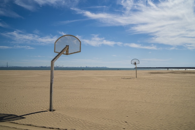 Anillos de baloncesto en la playa con un cielo azul nublado