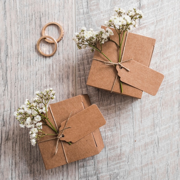 Anillos de boda con cajas de cartón sobre tabla de madera.