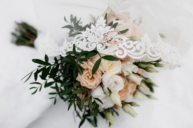 Los anillos de boda están en el velo de novia y flores.