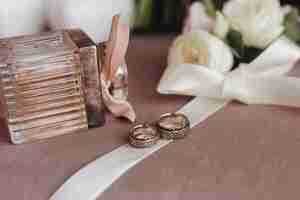Foto gratuita anillos de boda con grabado en la cinta cremosa, perfume y flores blancas.