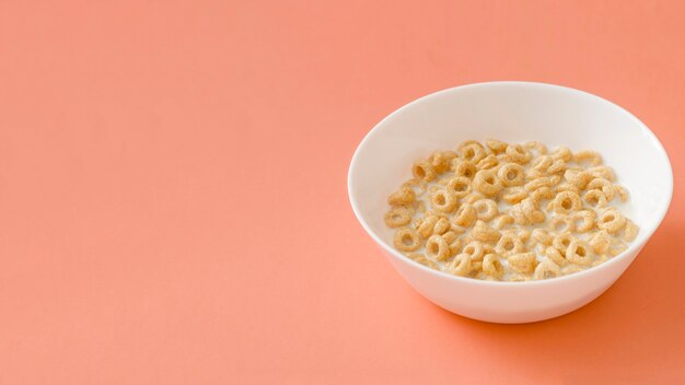 Anillos de cereales en el cuenco de leche sobre el fondo de color