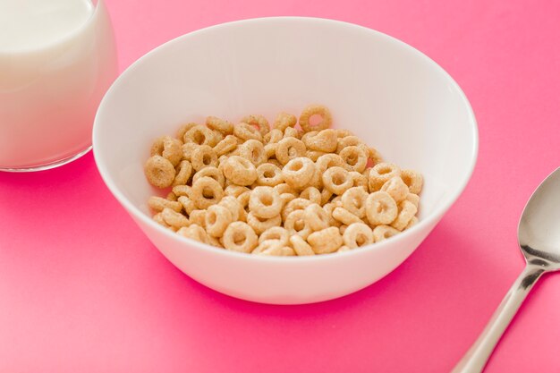 Anillos de cereales saludables en el cuenco blanco sobre fondo rosa