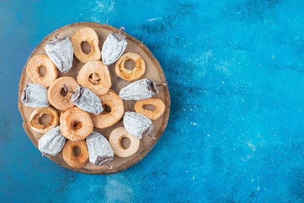 Foto gratuita anillos de manzana seca y caqui en una placa sobre la superficie azul