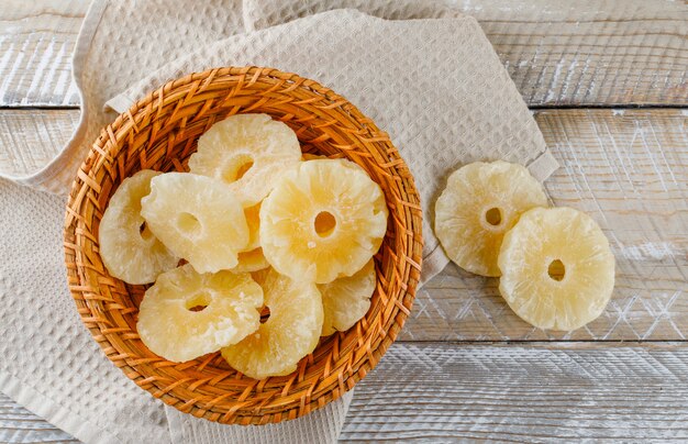 Anillos de piña secos en una cesta de mimbre sobre papel de cocina