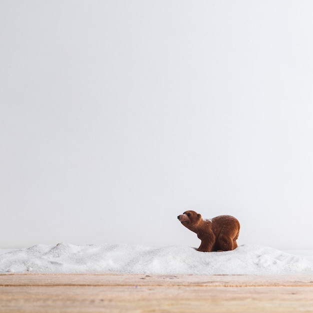 Foto gratuita animal de juguete cerca de tablero de madera y montón de nieve