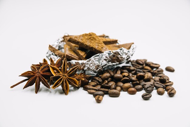 Anís estrellado; granos de café y trozos de chocolate sobre fondo blanco