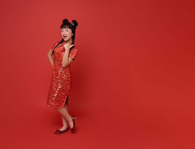 Año nuevo chino chica asiática con vestido tradicional de cheongsam qipao y manos que apuntan con el dedo