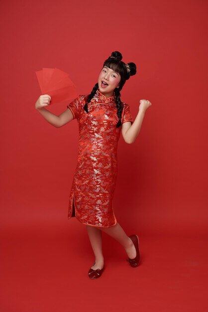 Año nuevo chino niña asiática con vestido tradicional de cheongsam qipao sosteniendo un sobre rojo