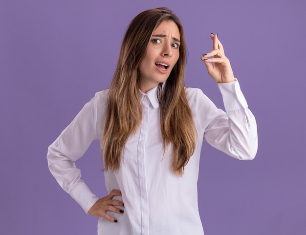 Foto gratuita ansiosa joven bastante caucásica cruzando los dedos aislados en la pared púrpura con espacio de copia