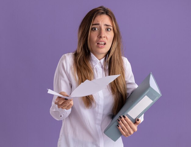 Ansiosa joven bastante caucásica sostiene hojas de papel y carpeta de archivos en púrpura