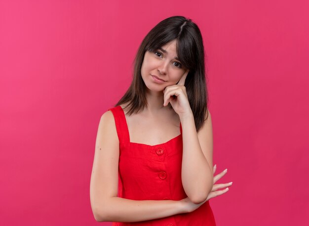 Ansiosa joven caucásica poniendo la mano en la barbilla mirando a la cámara sobre fondo rosa aislado con espacio de copia