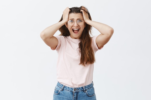 Ansioso y asustado joven morena con gafas posando