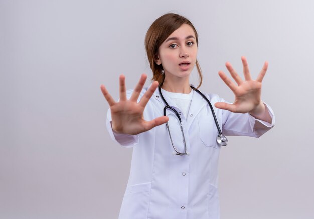 Ansioso joven doctora vistiendo bata médica y estetoscopio y sin hacer ningún gesto con espacio de copia