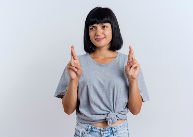 Ansioso joven morena mujer caucásica cruza los dedos mirando al lado