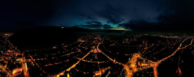 Antena drone amplia vista de Brasov en la noche Rumania Centro de la ciudad vieja Nightlights edificios carreteras