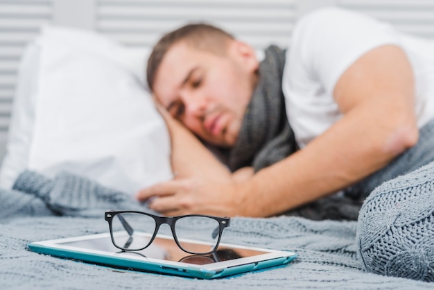 Foto gratuita anteojos en tableta digital frente a un hombre enfermo acostado sobre la cama