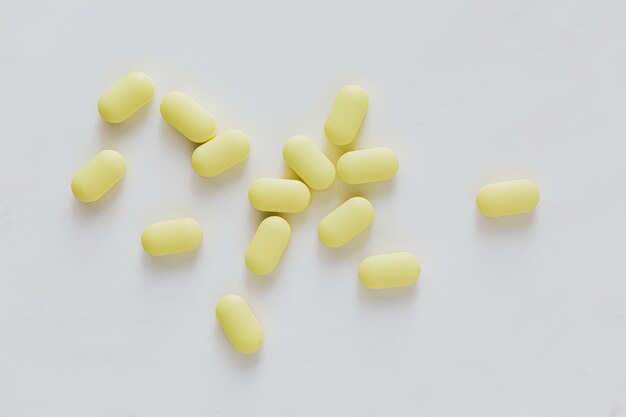 Antibióticos amarillos sobre una superficie blanca